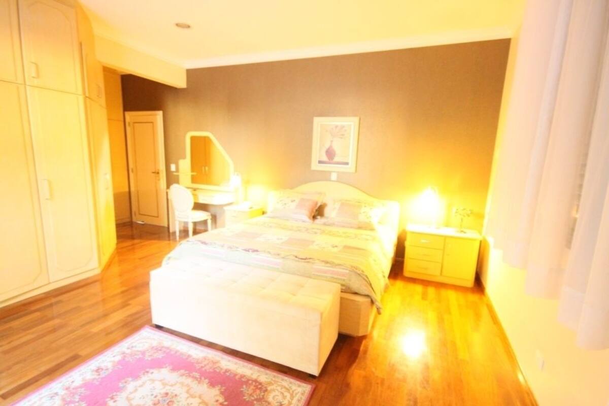 A bedroom with a bed, bedside tables, a chair, a wardrobe, and a mirror.