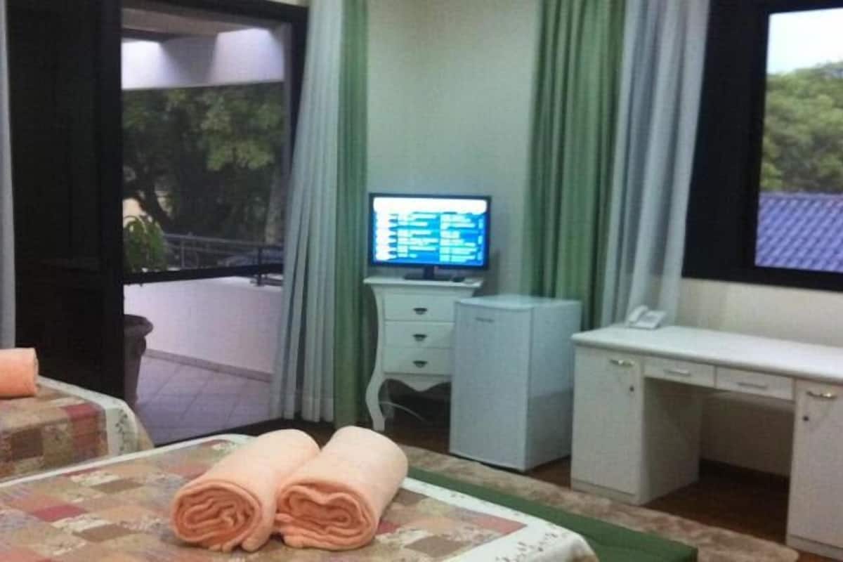 A hotel room with a bed, a desk, a television, and a view of the outdoors.