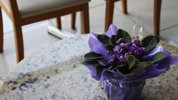 Uma pequena mesa com um arranjo de flores roxas, uma mesa redonda e cadeiras de madeira em um quarto.