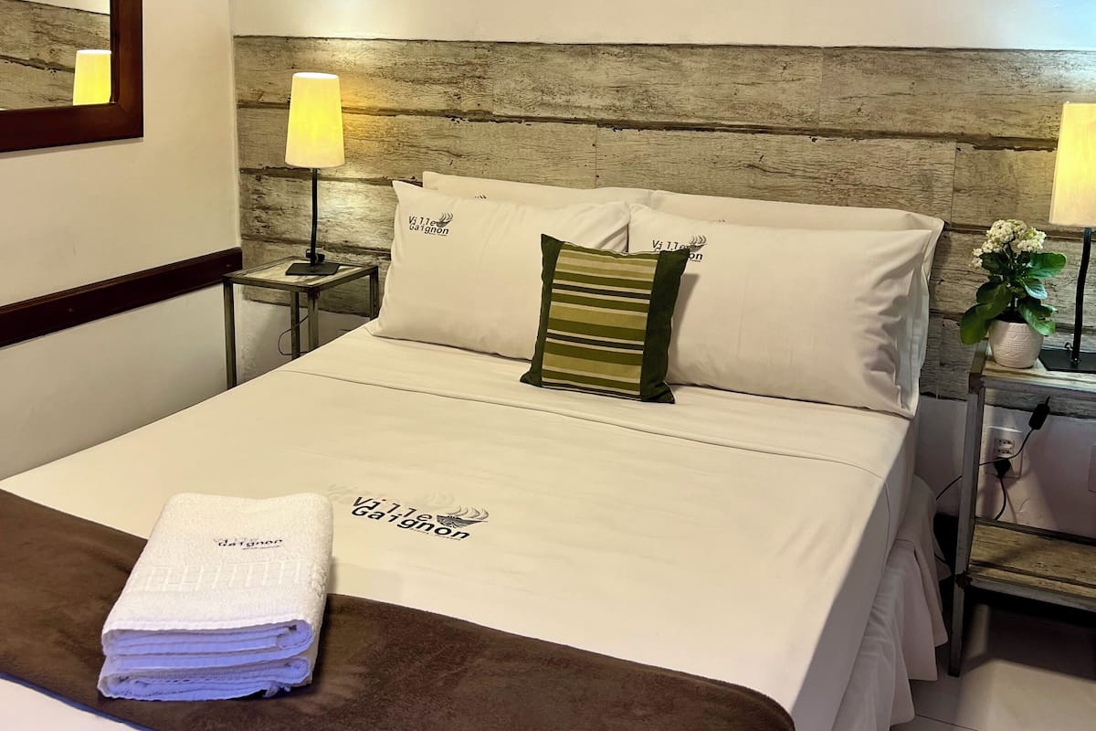 Ein Hotelzimmer mit einem großen Bett, zwei Nachttischen, einem Holzkopfende und Kunstwerken an den Wänden.