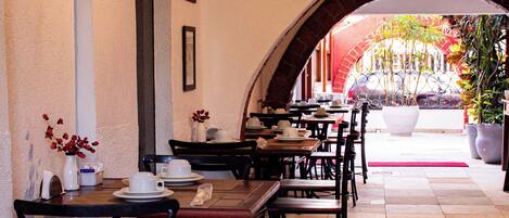 A restaurant with a long counter, black chairs, and framed pictures on the wall.