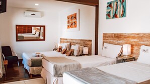Una habitación de hotel con dos camas, un escritorio, una silla y obras de arte en las paredes.