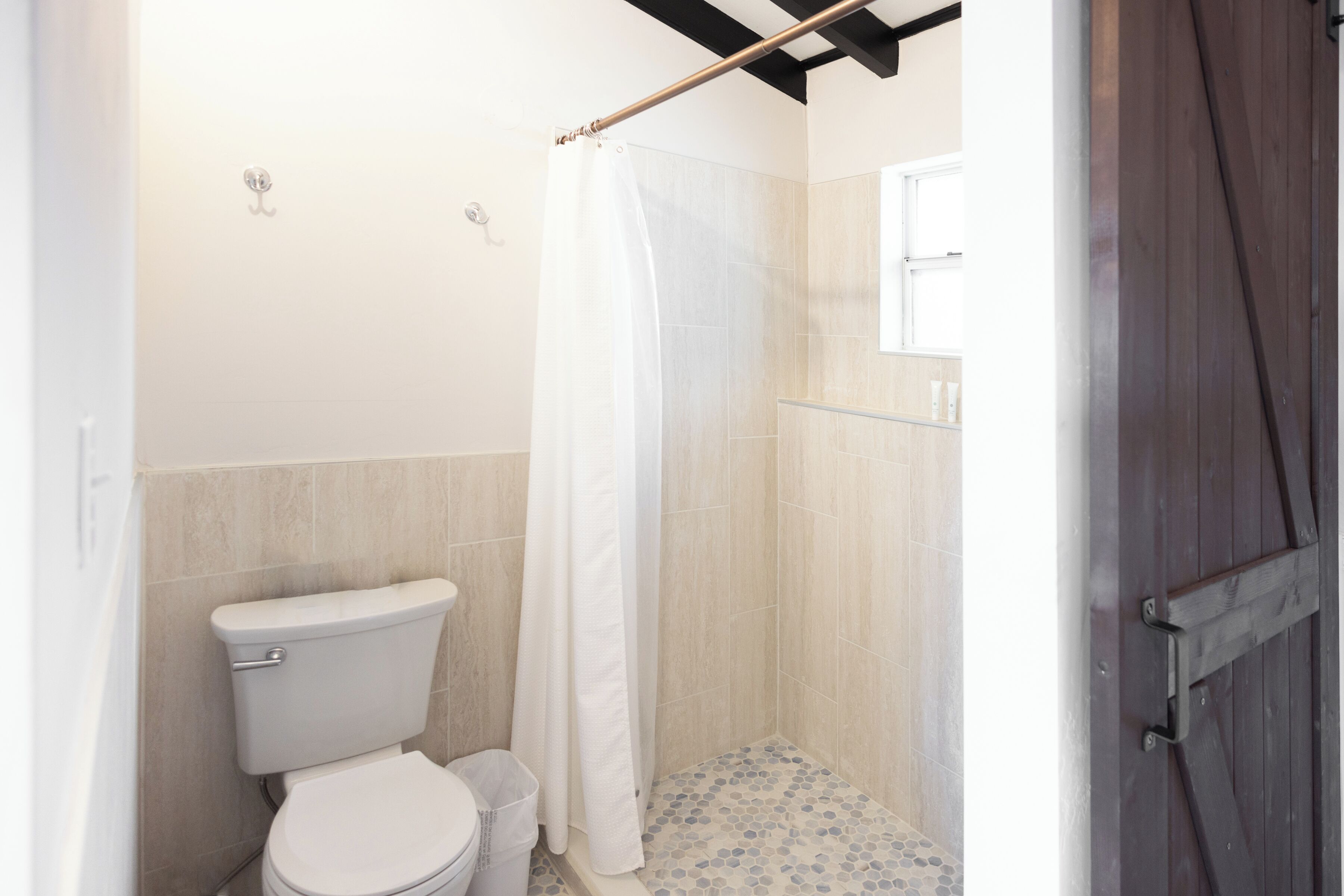 Une salle de bain avec des toilettes, une douche et une porte en bois.