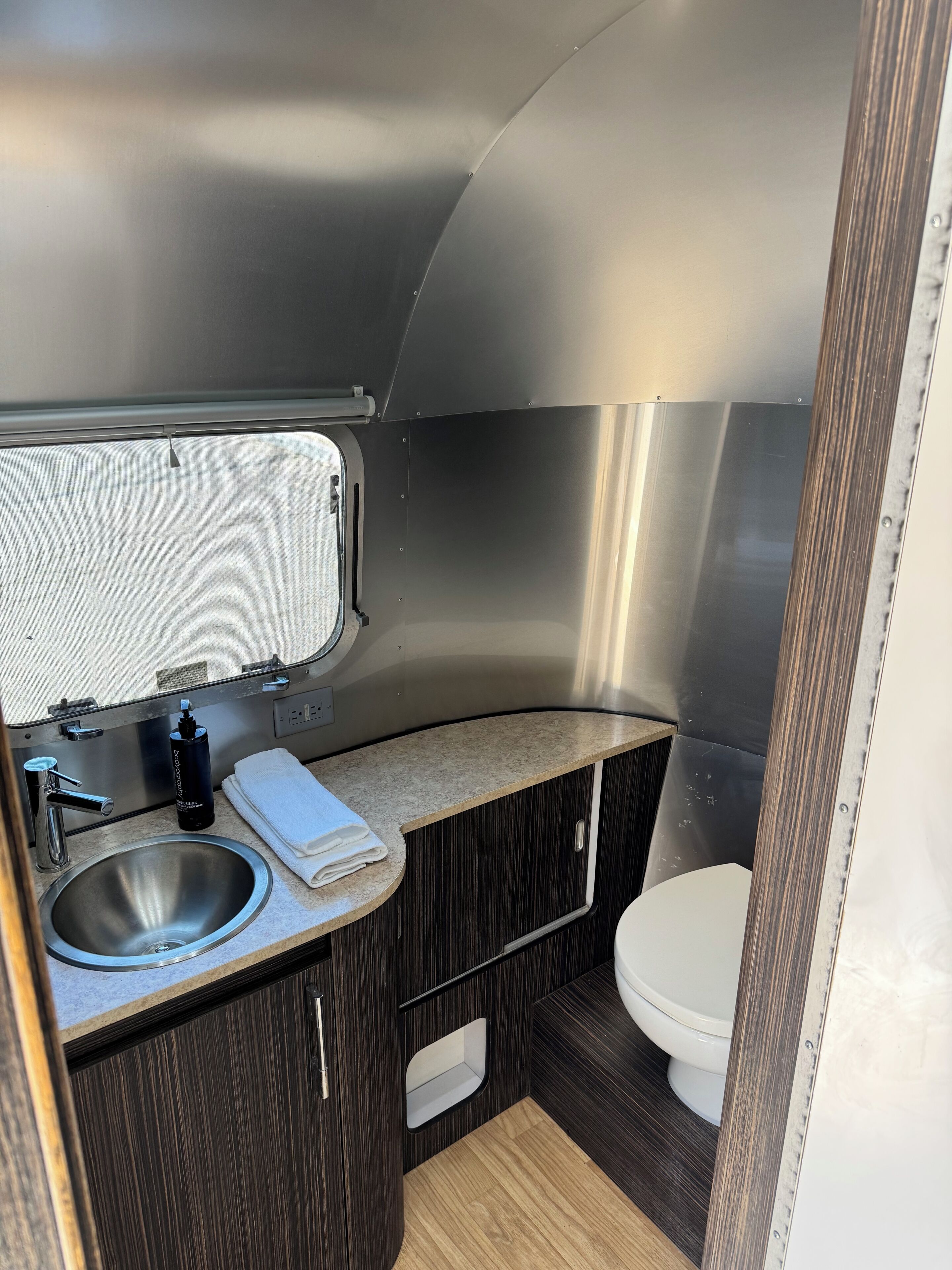 Een kleine, moderne badkamer met een wastafel, toilet en een raam.