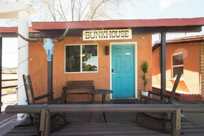 A Bunkhouse with a blue door, a wooden bench, and a table outside.