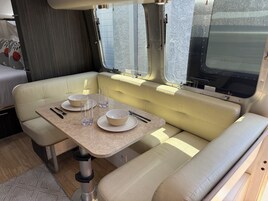 Un espacio habitable compacto con una mesa de comedor para dos personas, asientos acolchados y una ventana con vistas.