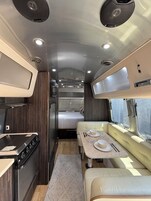 Interior compacto de una autocaravana con cocina americana, comedor, cama y baño pequeño.