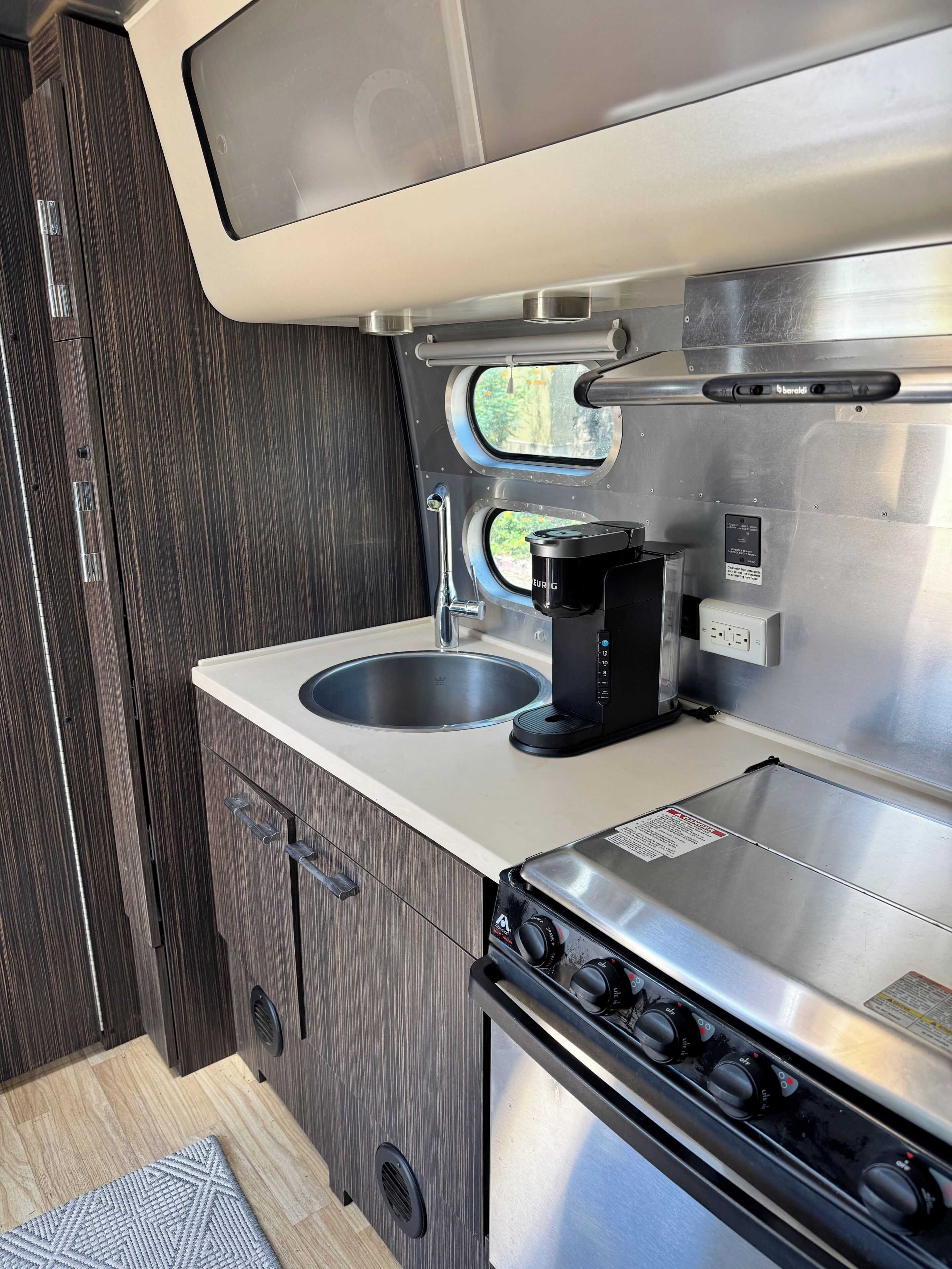 A compact kitchen with a sink, a coffee maker, and a stove.