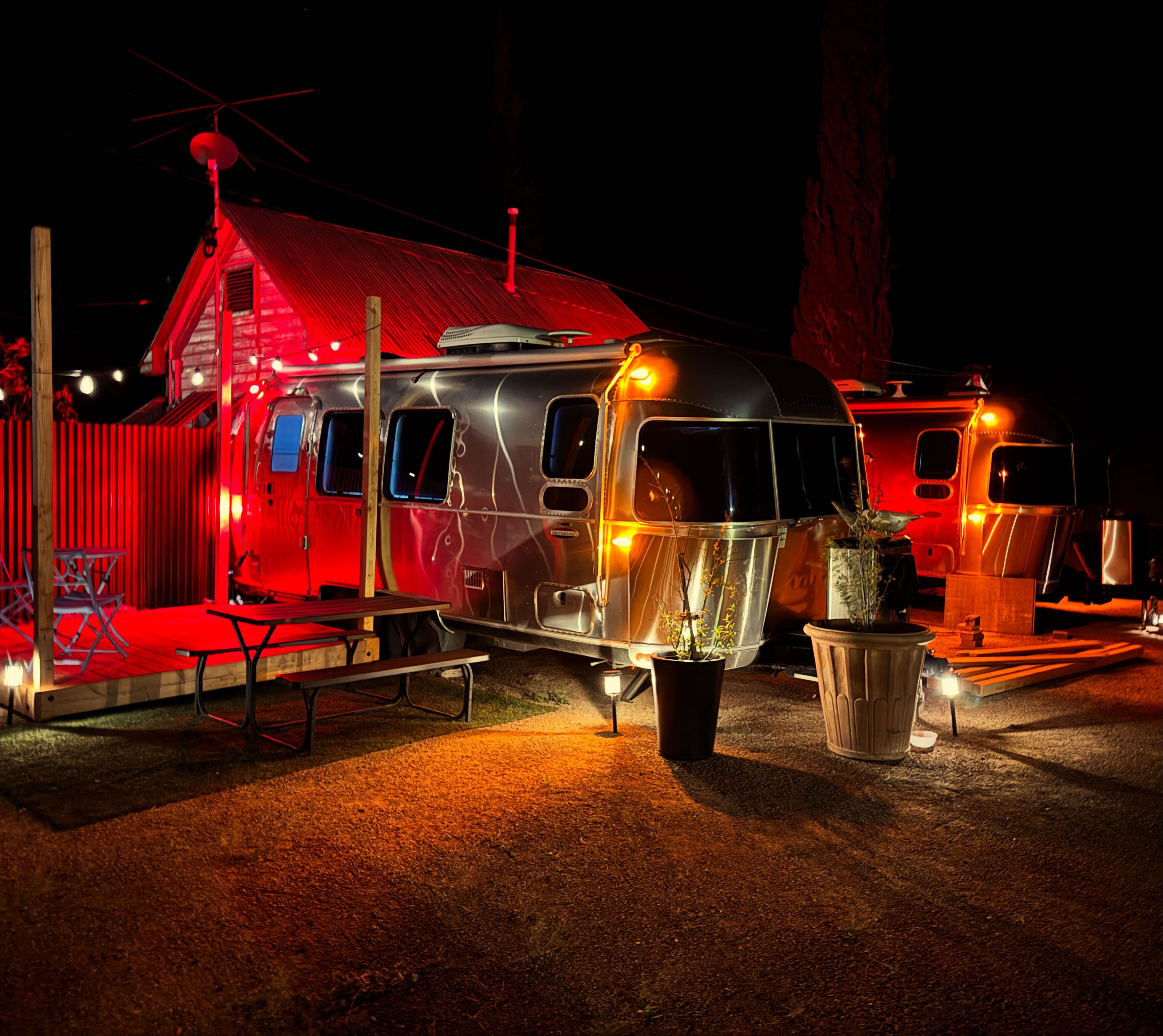 Vintage RVs parked in a lot with a red building in the background.