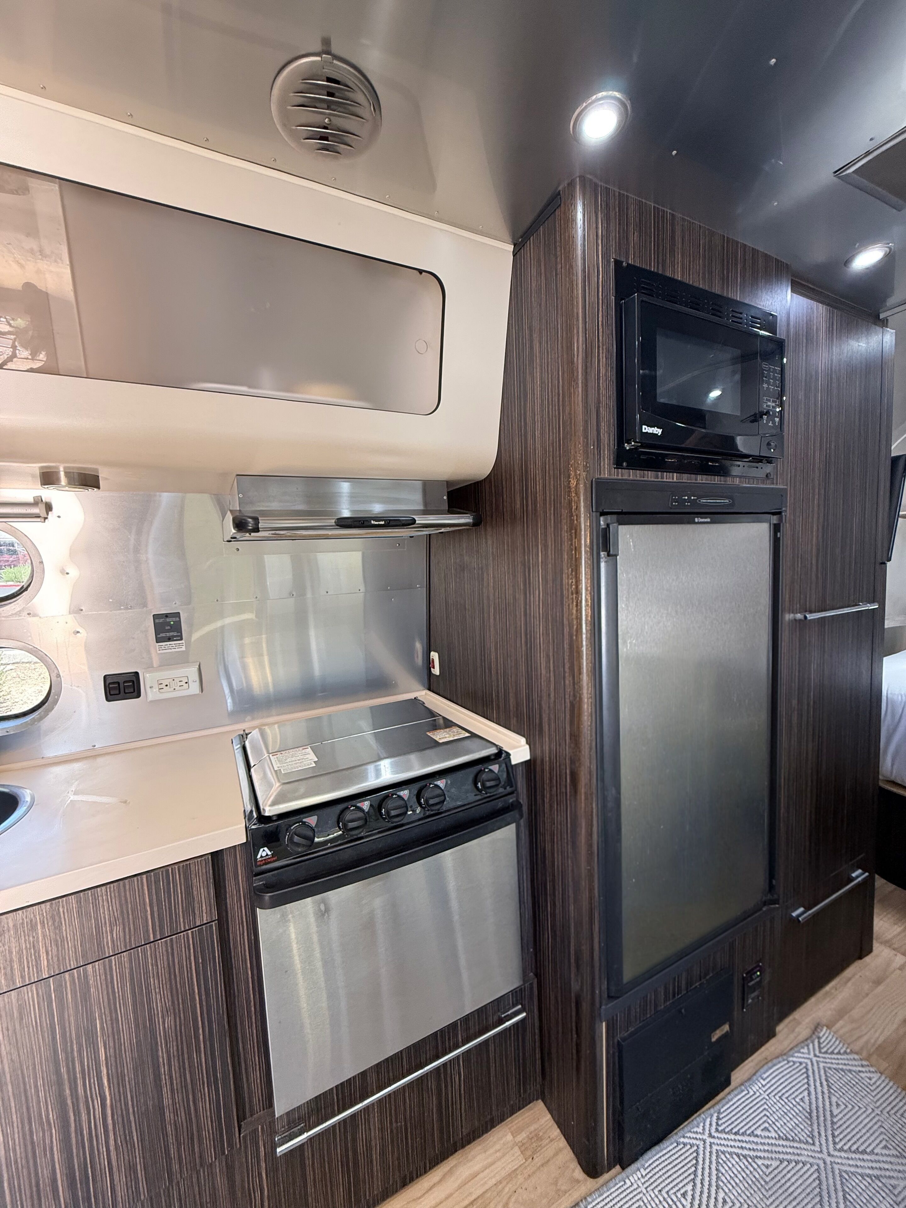 A compact kitchenette with a stove, microwave, and refrigerator.