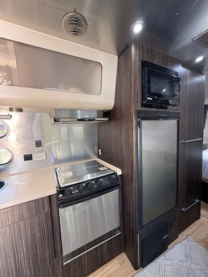 A compact kitchenette with a stove, microwave, and refrigerator.