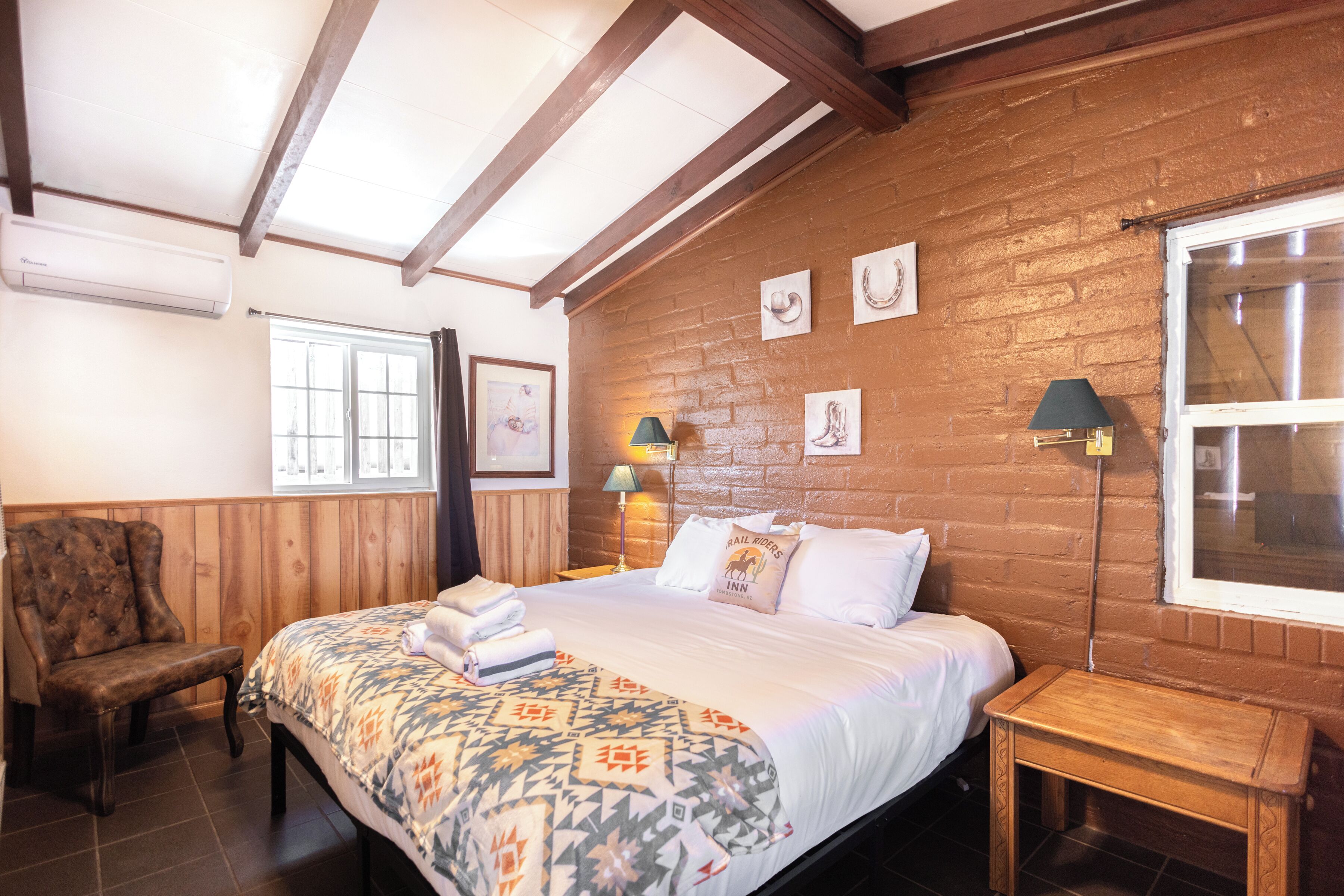 A bedroom with a bed, a chair, a bedside table, a lamp, and a window.