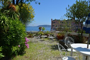 Une terrasse avec des sièges extérieurs, une vue sur la mer et un bâtiment en arrière-plan.