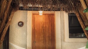 A thatched-roof entrance with a wooden door, a hammock, and a stone pillar with a sign. - Hotel Casa Colibri (Playa del Carmen)