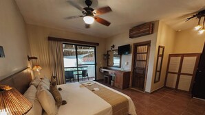 A hotel room with a bed, desk, and a balcony with a view. - Hotel Casa Colibri (Playa del Carmen)
