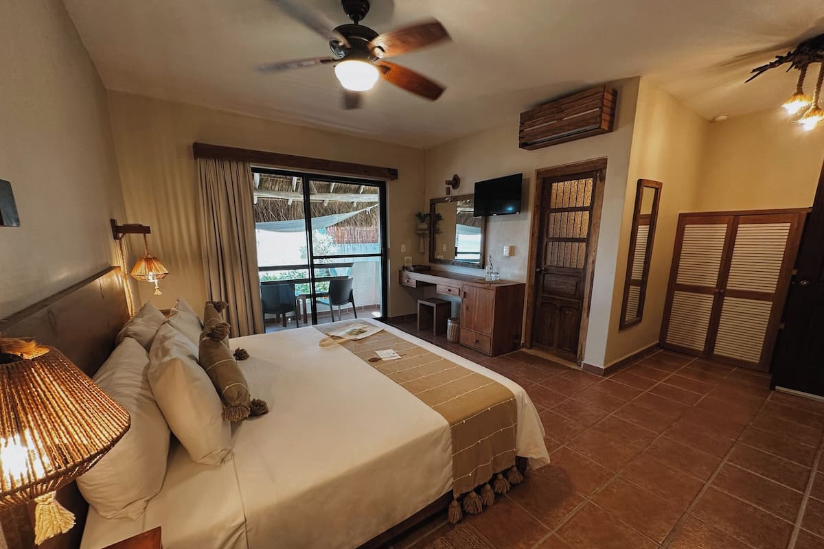 A hotel room with a bed, desk, and a balcony with a view.