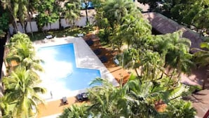 A pool surrounded by palm trees and a white building. - Lanville Athenee (Foz do Iguacu)