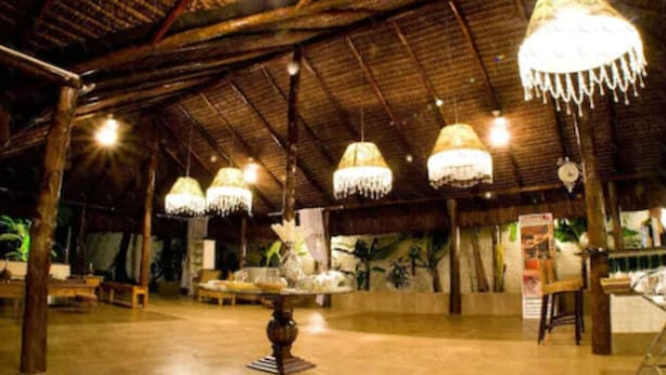 A spacious indoor area with high ceilings and hanging chandeliers. There are tables and chairs arranged for dining or socializing. - Lanville Athenee (Foz do Iguacu)