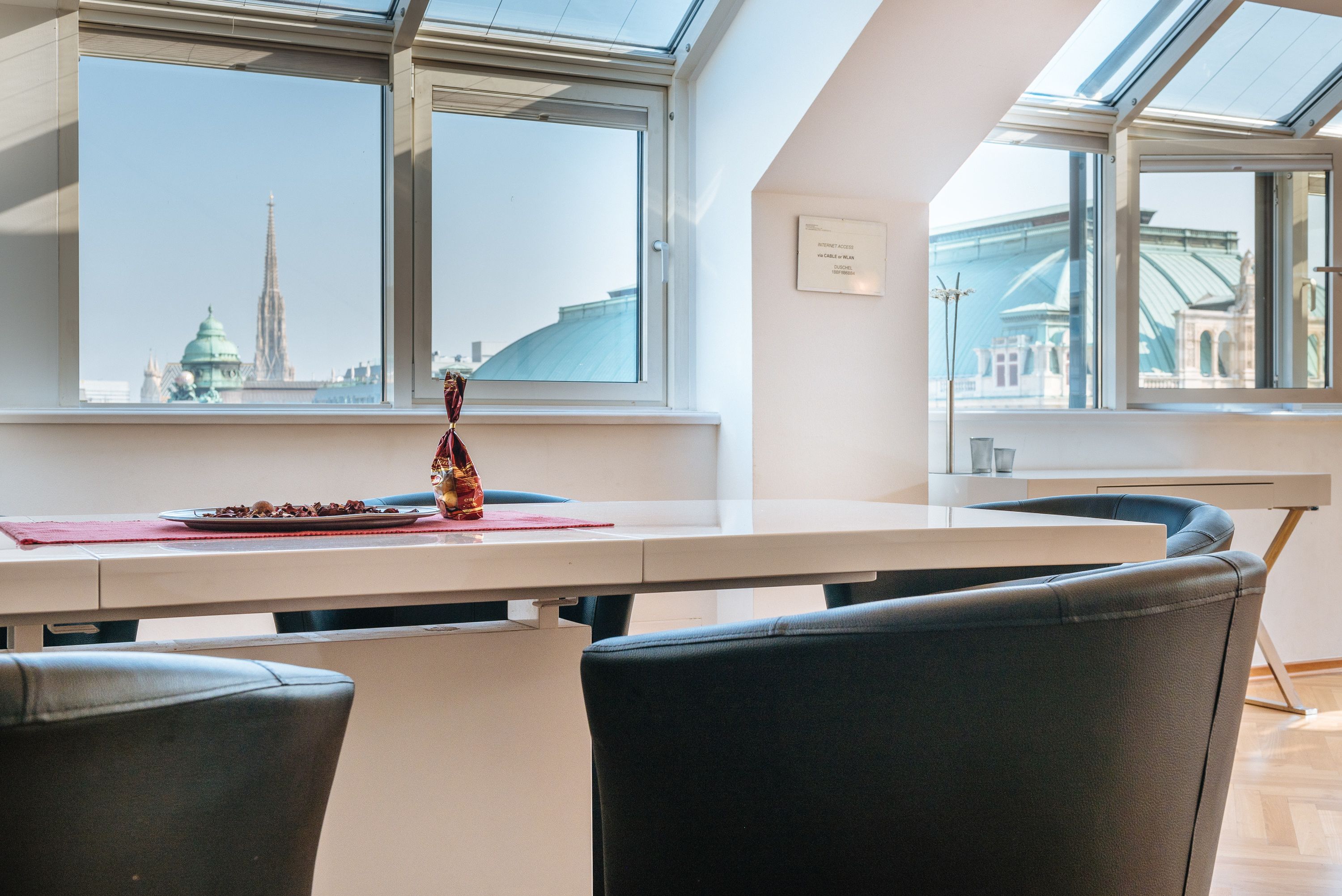 A modern dining area with a large window offering a view of a city skyline, including a prominent tower.