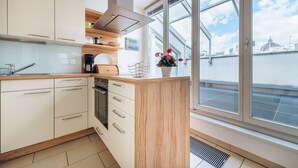 Een moderne keuken met witte kasten, een houten aanrechtblad en een groot raam met uitzicht op de stad.