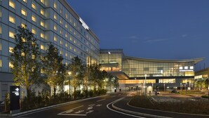 A modern hotel with a curved glass facade, multiple floors, and a well-lit entrance area. - The Royal Park Hotel Tokyo Haneda Airport Terminal 3 (Tokyo)