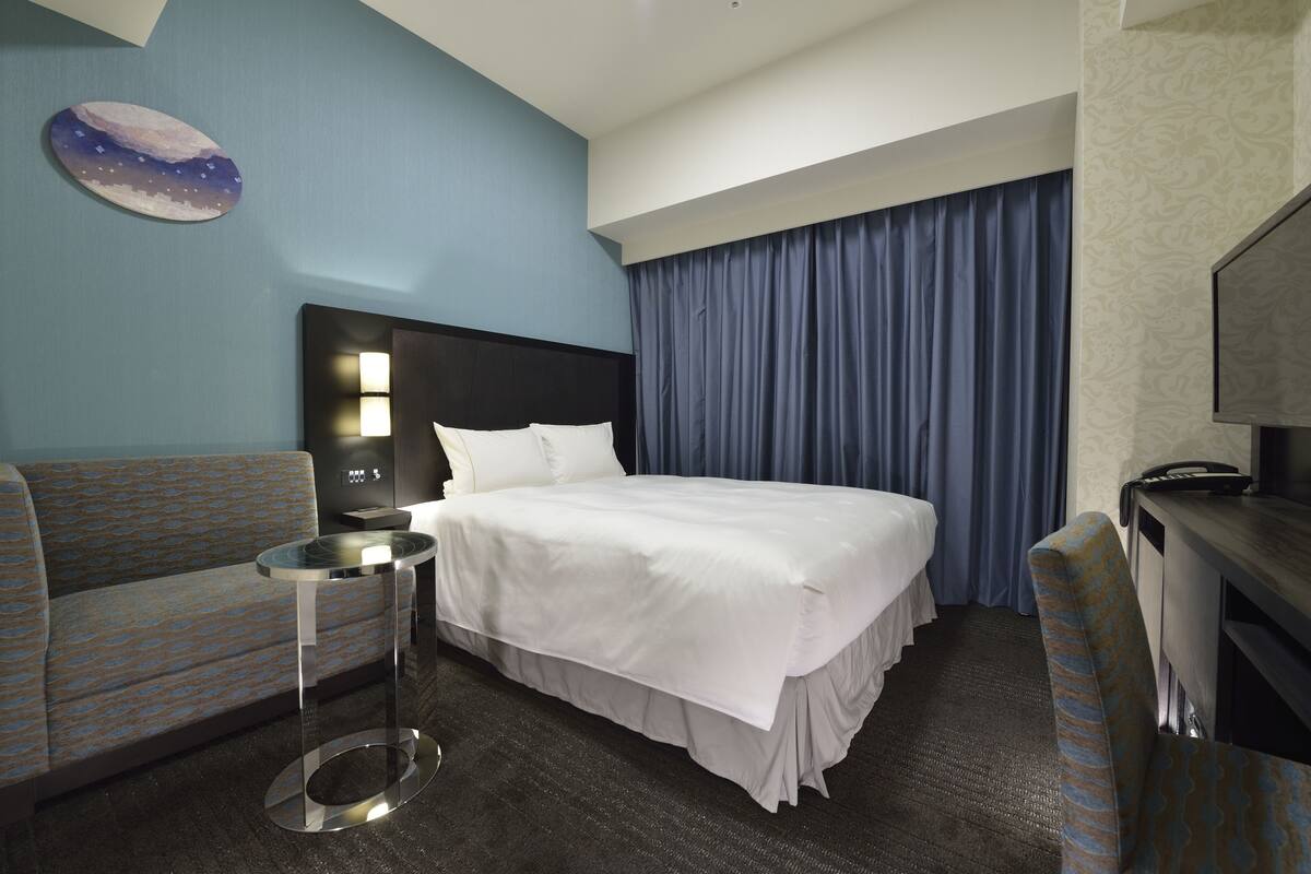 Une chambre d’hôtel avec un lit, un canapé, une petite table et un téléviseur.