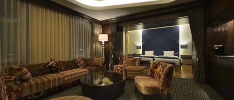 A modern hotel room with a sofa set, a round coffee table, and a bed with a headboard.