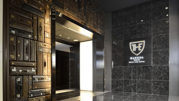 A lobby with a wall of stacked suitcases and a sign for the Haneda Tokyo Royal Park Hotel. - The Royal Park Hotel Tokyo Haneda Airport Terminal 3 (Tokyo)