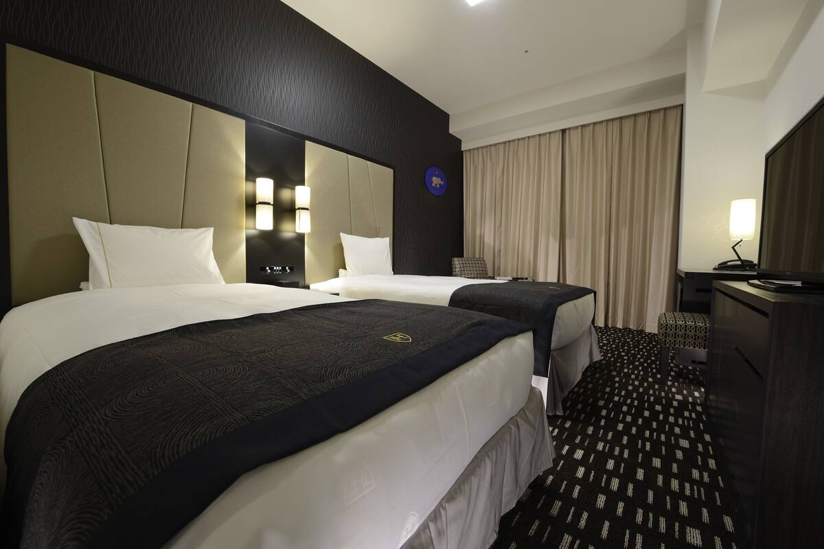 Une chambre d’hôtel avec deux lits, un bureau et une chaise.