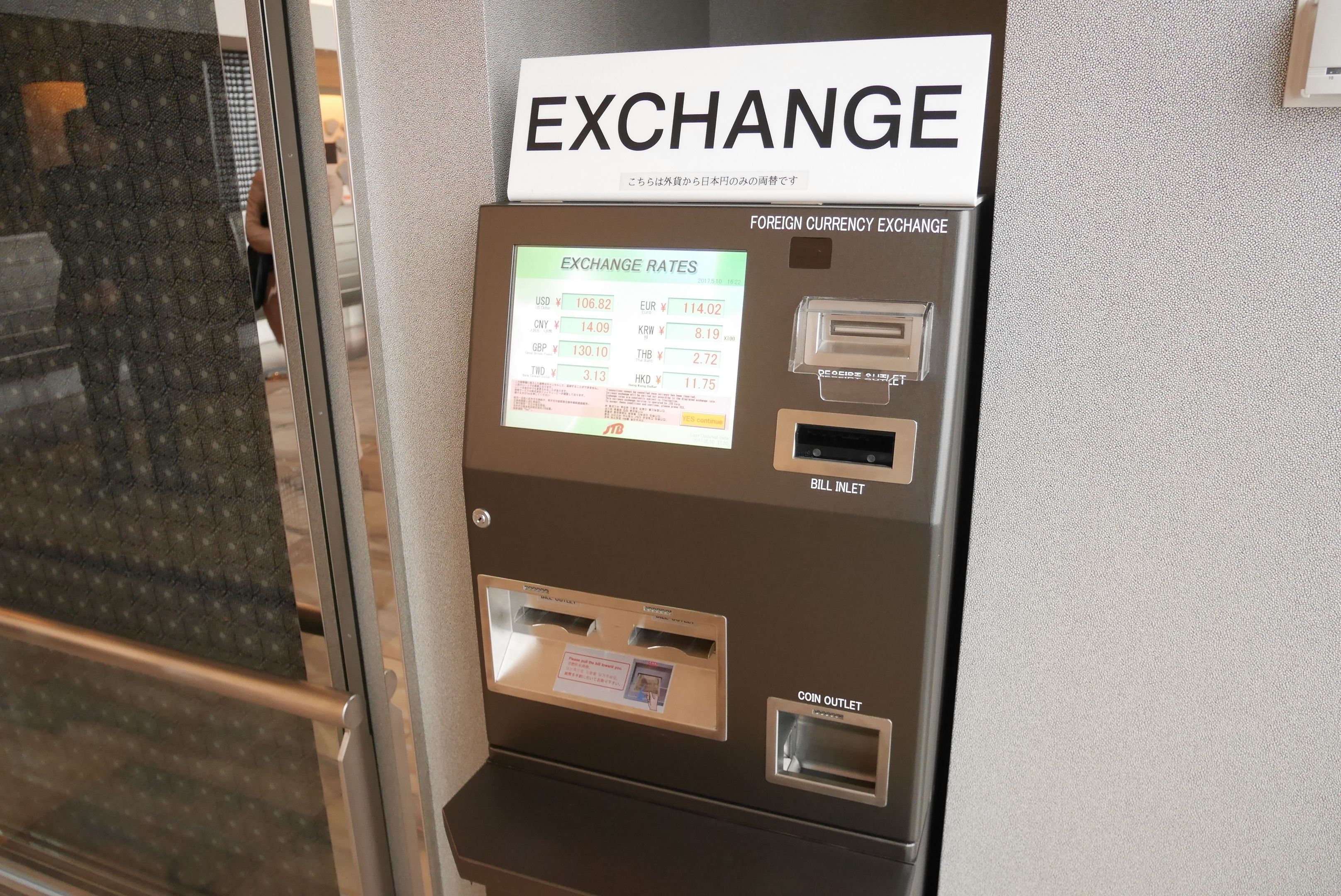 A currency exchange machine with a sign indicating foreign currency exchange rates.