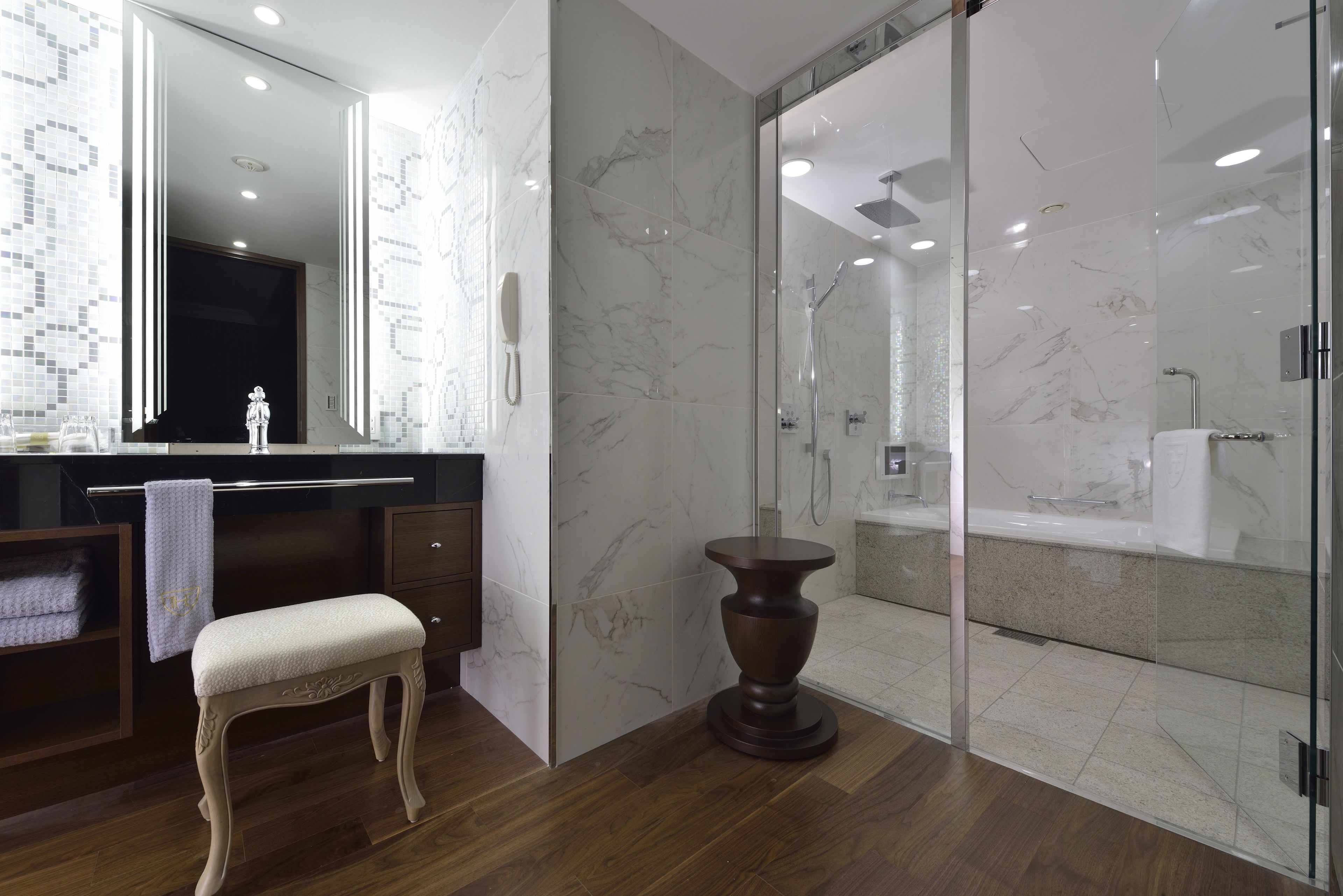 Une salle de bain moderne avec un meuble-lavabo en marbre, une cabine de douche en verre et un banc en bois.