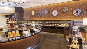 A buffet area with various food items and beverages, a wooden wall with clocks, and a modern design. - The Royal Park Hotel Tokyo Haneda Airport Terminal 3 (Tokyo)