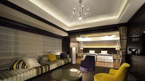 Una habitación de hotel moderna con sofá, sillón y una mesa redonda de centro.