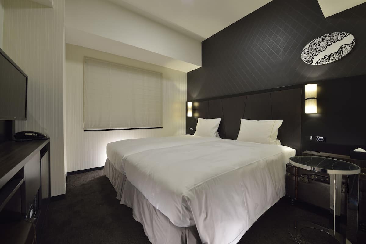 Une chambre d’hôtel avec un grand lit, un bureau, une chaise et une petite table.