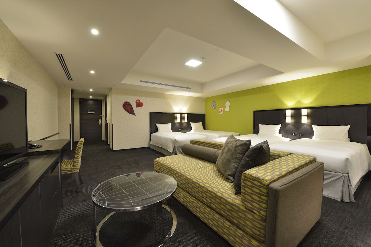 Una habitación de hotel con dos camas, un sofá, un televisor y un escritorio.