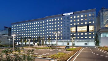 Um grande edifício de hotel com vários andares e um estacionamento à frente.