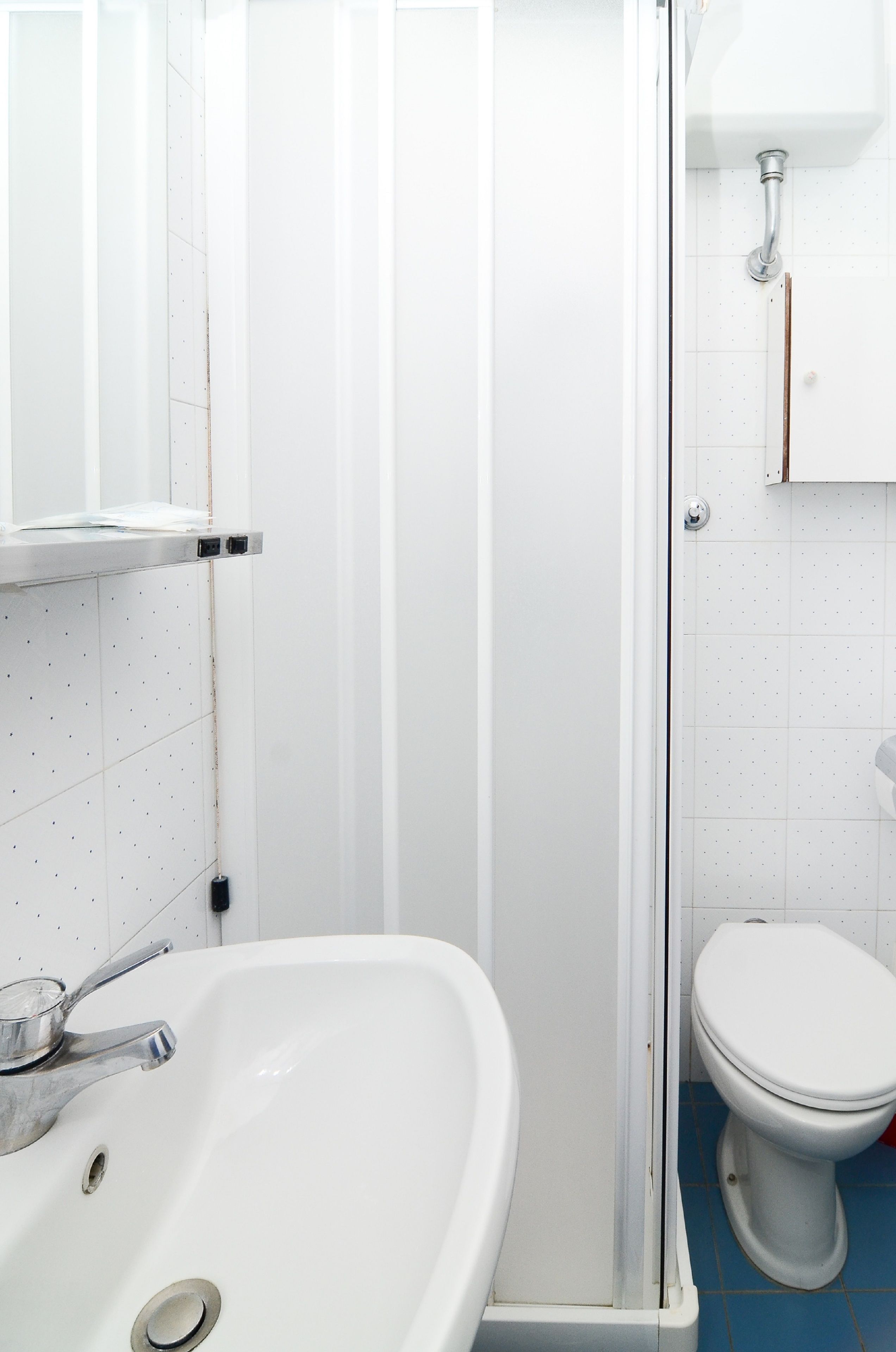 Ein Badezimmer mit einem weißen Waschbecken, einer Toilette und einer Duschkabine.