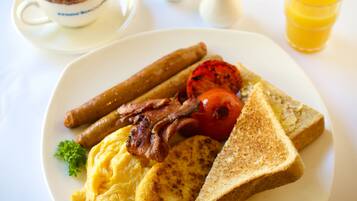 Une assiette de nourriture pour le petit-déjeuner comprenant des œufs, du bacon, des saucisses, des toasts et une tomate.