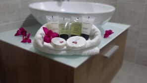 A bathroom vanity with a white sink, toiletries, and decorative flowers.