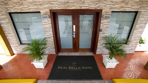 L’entrée d’un hôtel, avec une façade en pierre, une double porte et un paillasson.