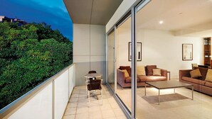 A modern living room with a glass wall, a sofa set, and a small table. - Brighton Bay Apartments (Brighton)