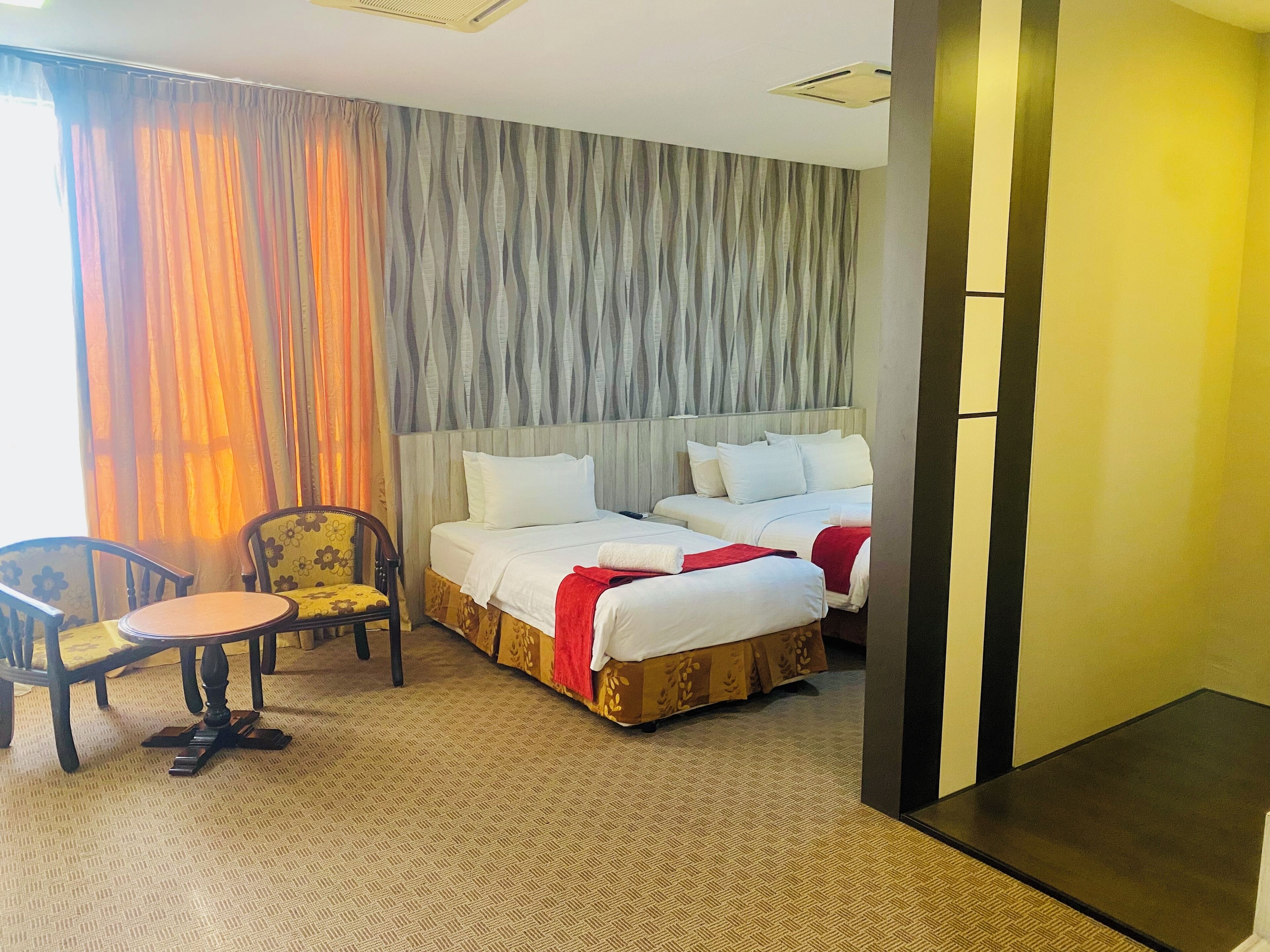 Une chambre d’hôtel avec un lit double, une petite table ronde, une chaise et une moquette à motifs.