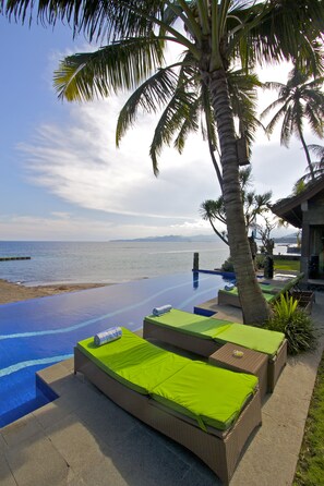A poolside area with lounge chairs and a view of the sea.