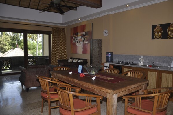 A dining area with a wooden table and chairs, a coffee machine, and a view of the outdoors.