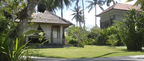 A tropical resort with a thatched-roof building, lush greenery, and palm trees.