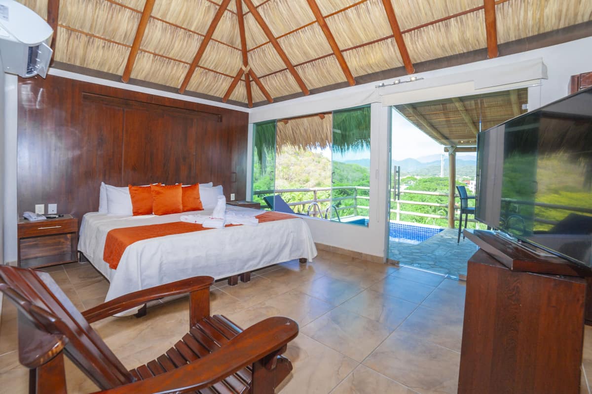 A hotel room with a bed, wooden furniture, a TV, and a balcony with a view.