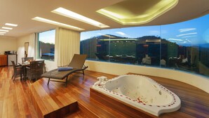 Una habitación moderna con un ventanal grande, suelo de madera, jacuzzi y zona de estar.