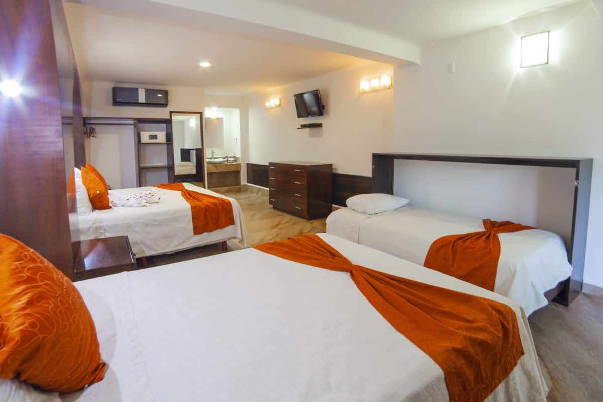 A hotel room with two beds, a dresser, a television, and a mirror.