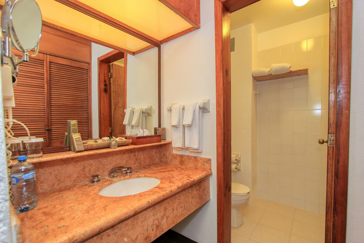 Un baño con lavabo de mármol, un espejo, toallero y zona de ducha.