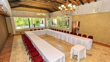 Un salón de conferencias con una larga mesa, sillas rojas y ventanas amplias.